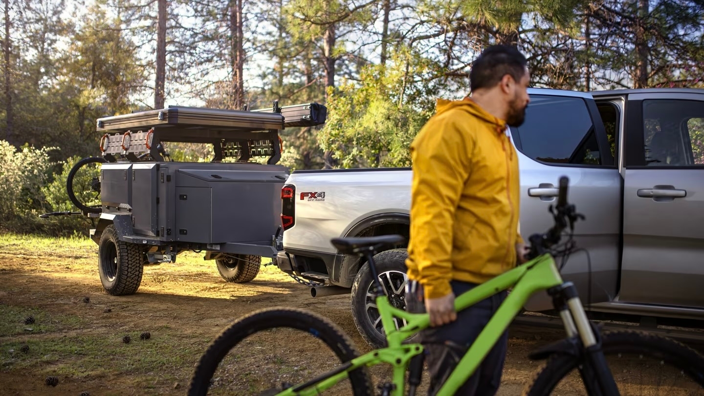 Un Homme qui regarde son Ford Ranger 2024 avec une remorque attelé en arrière.